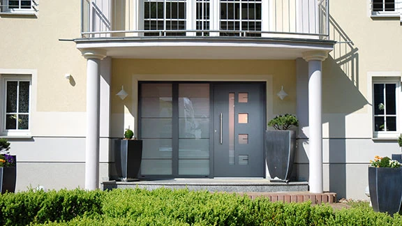 Moderner Hauseingang mit grauer Haustür, Vordach und Säulen am Neubau