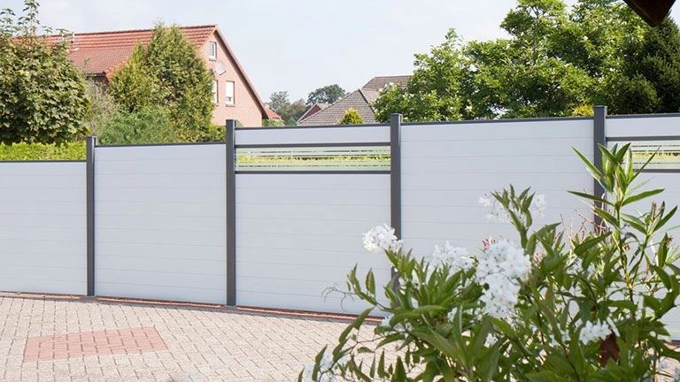 Moderner Sichtschutzzaun aus Aluminium im Garten vor Wohnhaus und Hecken
