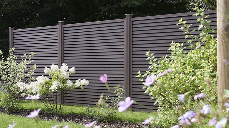 Moderner Sichtschutzzaun aus WPC in Anthrazit im Garten mit Blumenbeet